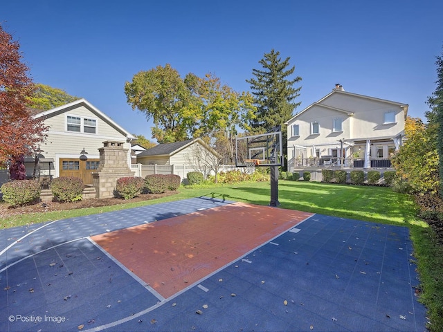 view of sport court with basketball hoop and a yard