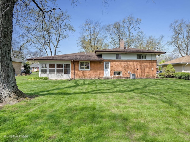 back of property featuring a lawn, brick siding, and a chimney