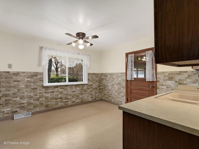 kitchen featuring a ceiling fan, visible vents, wainscoting, dark brown cabinets, and a sink