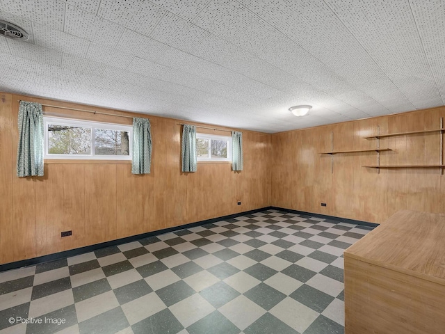 below grade area featuring visible vents, wooden walls, and dark floors