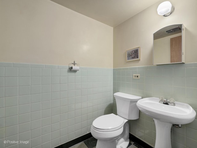 bathroom with toilet, tile walls, visible vents, and a wainscoted wall
