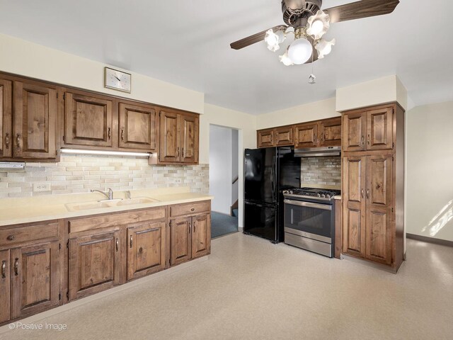 kitchen with decorative backsplash, freestanding refrigerator, ceiling fan, stainless steel range with gas cooktop, and a sink