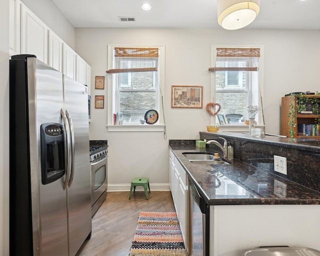 kitchen featuring appliances with stainless steel finishes, a sink, healthy amount of natural light, white cabinets, and recessed lighting