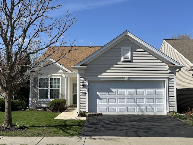 single story home with a garage, a front lawn, roof with shingles, and driveway