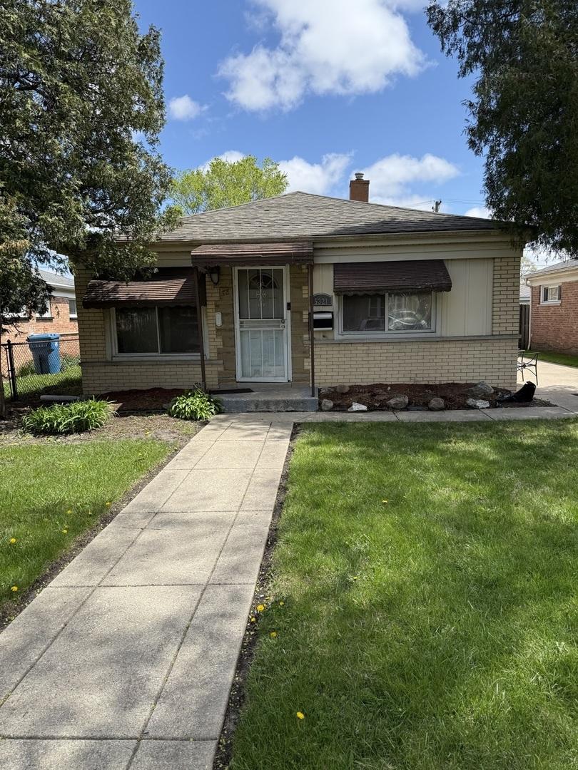 bungalow-style home featuring a front lawn, fence, a chimney, and brick siding