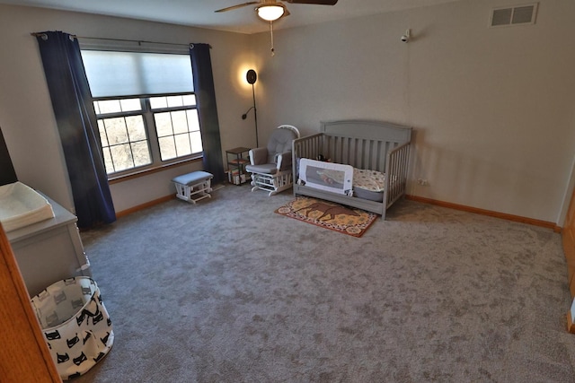 bedroom featuring visible vents, carpet floors, baseboards, a crib, and a ceiling fan