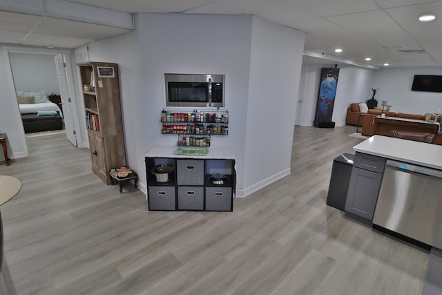 kitchen with stainless steel appliances, baseboards, a paneled ceiling, and light wood finished floors