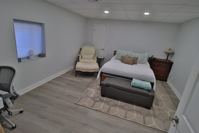 bedroom featuring baseboards, visible vents, wood finished floors, and a paneled ceiling