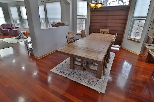 dining room with baseboards, arched walkways, and wood finished floors