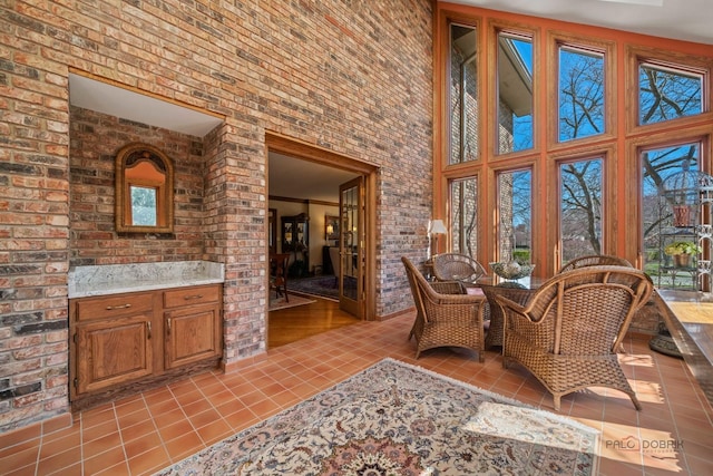 1330 Kurtis Ln, Lake Forest, IL 60045 - living area featuring light tile patterned flooring, a towering ceiling, healthy amount of natural light, and brick wall