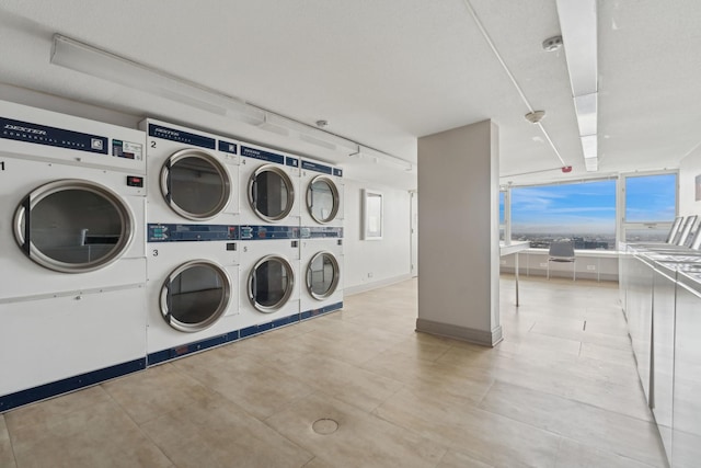 community laundry room with stacked washer / drying machine, baseboards, separate washer and dryer, and a healthy amount of sunlight