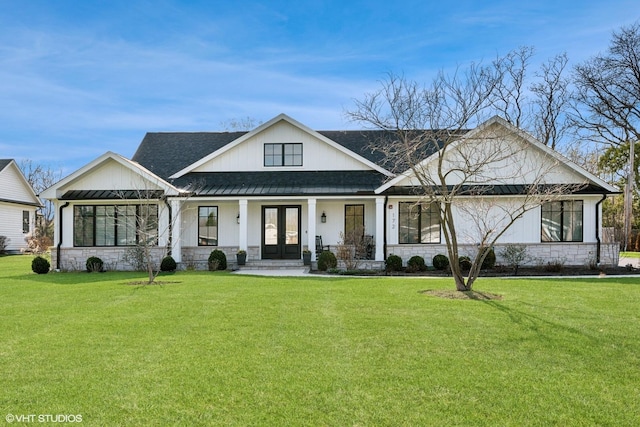 modern inspired farmhouse with french doors, a front yard, stone siding, and a standing seam roof