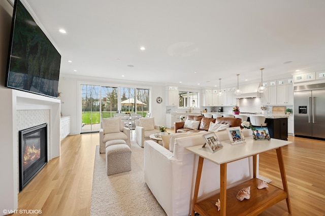 living area featuring light wood finished floors, plenty of natural light, recessed lighting, and a glass covered fireplace