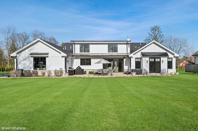 rear view of house with a standing seam roof, metal roof, and a yard