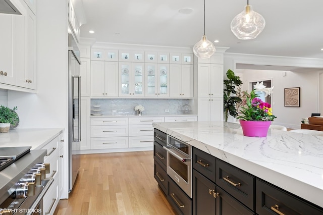 kitchen with white cabinets, decorative backsplash, decorative light fixtures, glass insert cabinets, and ornamental molding