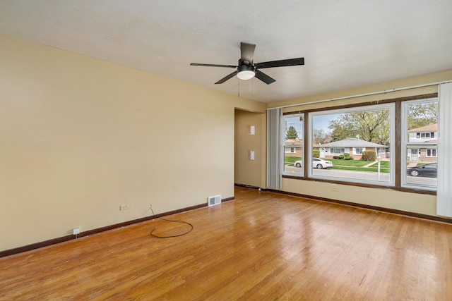 empty room featuring visible vents, light wood finished floors, baseboards, and ceiling fan
