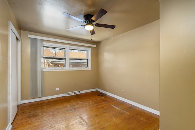 spare room with baseboards, visible vents, a ceiling fan, and hardwood / wood-style flooring