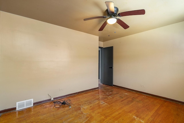 spare room featuring light wood finished floors, baseboards, visible vents, and ceiling fan