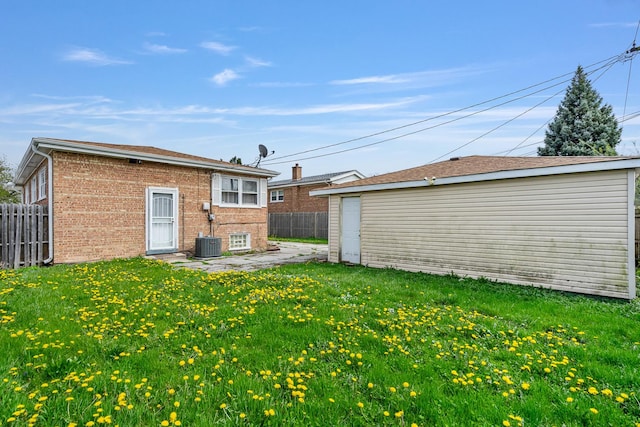 back of house with a patio area, a lawn, an outdoor structure, fence, and brick siding