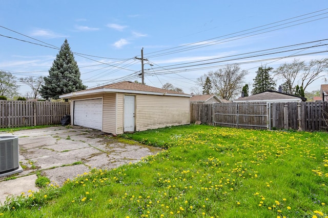 view of yard with a fenced backyard, an outdoor structure, central air condition unit, and a detached garage