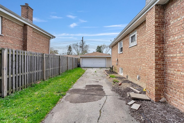 exterior space featuring fence, an outbuilding, brick siding, and a detached garage