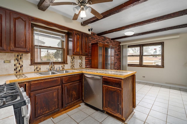 kitchen featuring a peninsula, a sink, a ceiling fan, appliances with stainless steel finishes, and light tile patterned floors