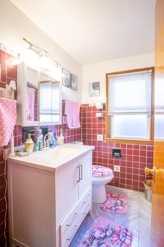 bathroom with tile walls, vanity, and toilet