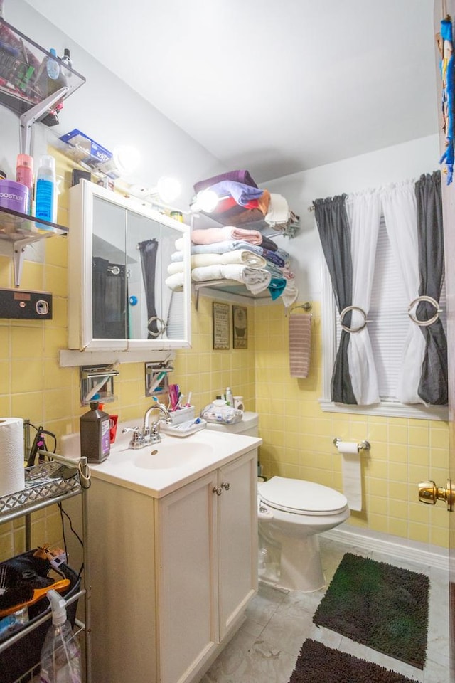 bathroom with toilet, vanity, and tile walls