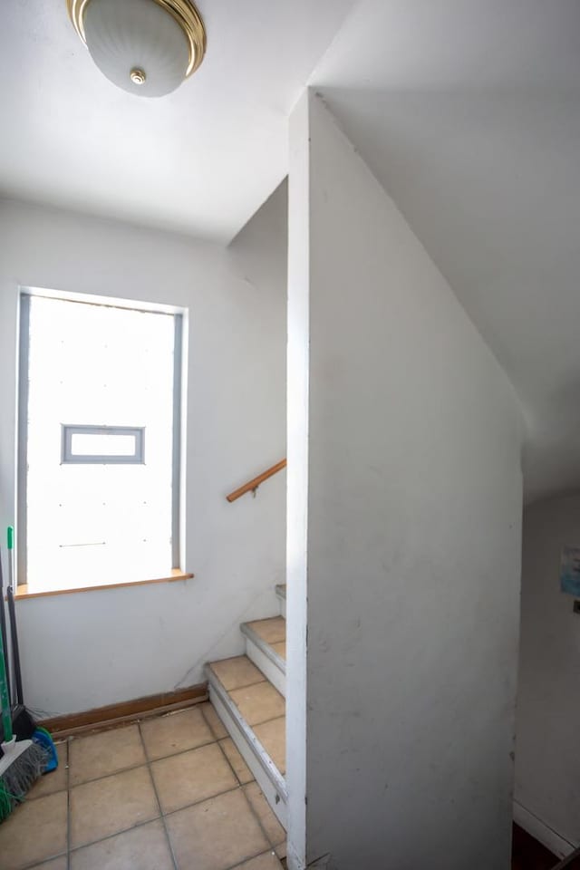 stairway with tile patterned floors and vaulted ceiling