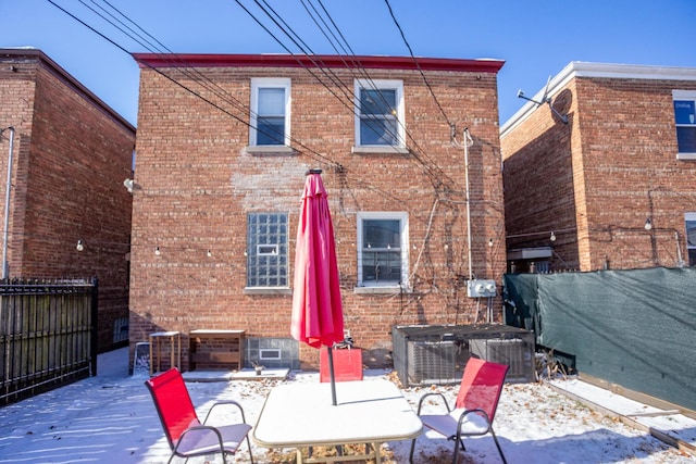 rear view of house with central air condition unit, brick siding, and fence