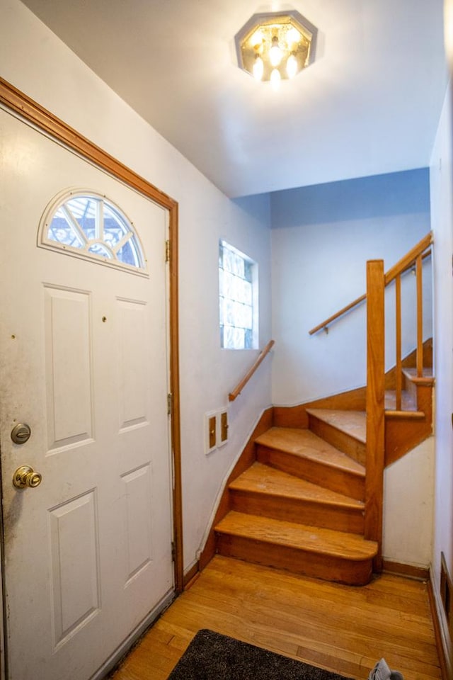 foyer featuring baseboards, wood finished floors, and stairway