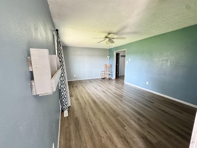26812 US-150 Hwy, Leroy, IL 61752 - unfurnished living room with a ceiling fan, dark wood-style flooring, a textured ceiling, baseboards, and a textured wall