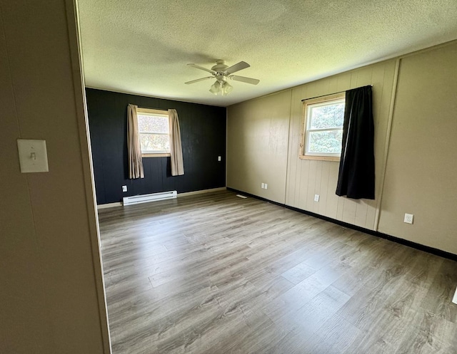 26812 US-150 Hwy, Leroy, IL 61752 - empty room with baseboard heating, wood finished floors, plenty of natural light, a ceiling fan, and a textured ceiling