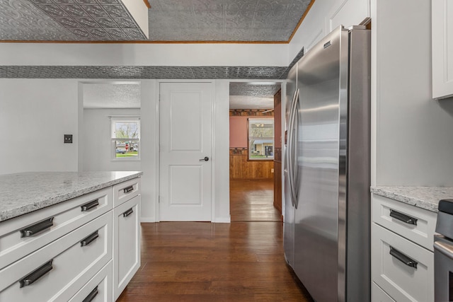 kitchen featuring white cabinets, freestanding refrigerator, light stone countertops, and dark wood finished floors