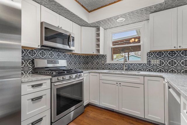 kitchen featuring white cabinets, a sink, light stone countertops, dark wood-type flooring, and appliances with stainless steel finishes