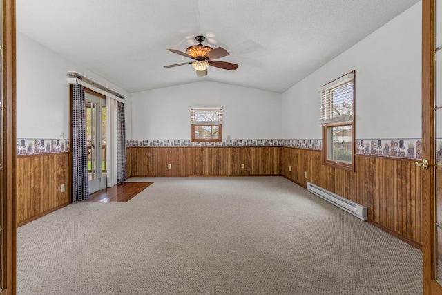 empty room featuring wainscoting, a baseboard radiator, wood walls, and carpet