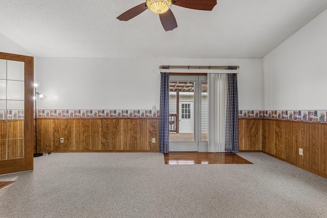 spare room featuring a wainscoted wall, wooden walls, and carpet flooring