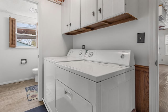 washroom featuring light wood-style flooring, baseboards, washer and dryer, and cabinet space