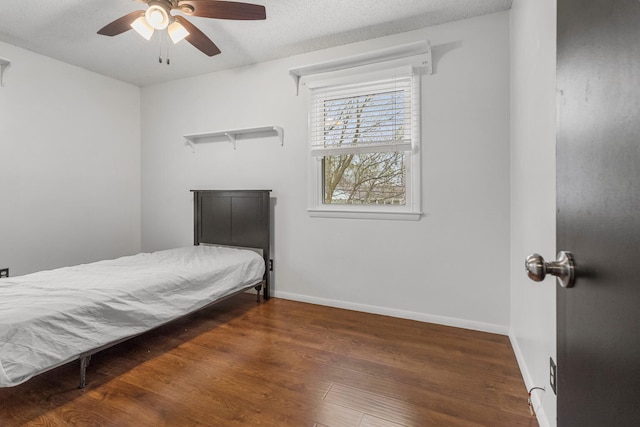 bedroom featuring baseboards, wood finished floors, and ceiling fan