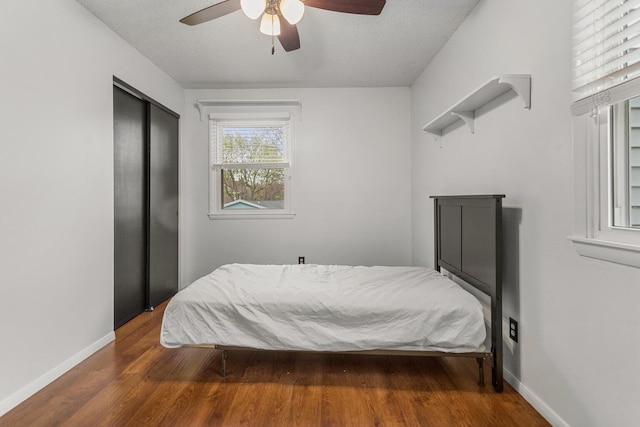 bedroom with wood finished floors, a closet, a ceiling fan, and baseboards