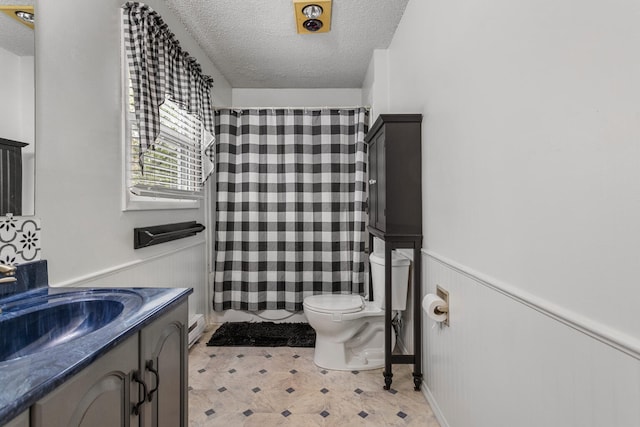 bathroom featuring a wainscoted wall, toilet, vanity, a shower with shower curtain, and a textured ceiling