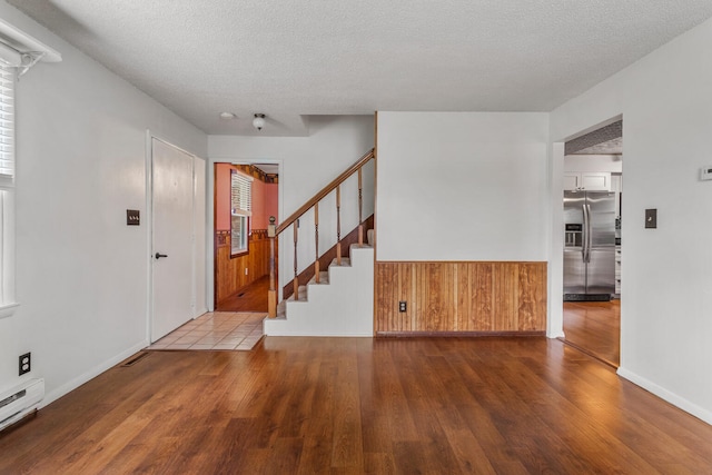 foyer entrance featuring a baseboard radiator, wood finished floors, and a textured ceiling