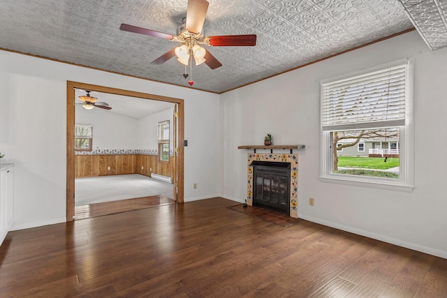unfurnished living room featuring a ceiling fan, ornamental molding, wood finished floors, and a healthy amount of sunlight