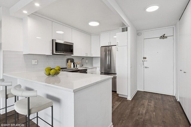 1560 N Sandburg Ter Unit 3207J, Chicago, IL 60610 - kitchen featuring a breakfast bar area, appliances with stainless steel finishes, visible vents, light countertops, and a peninsula