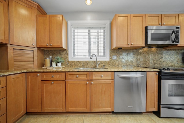 kitchen featuring a sink, light stone counters, backsplash, and stainless steel appliances