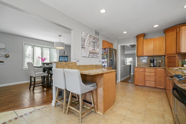 kitchen with baseboards, a kitchen bar, recessed lighting, tasteful backsplash, and range