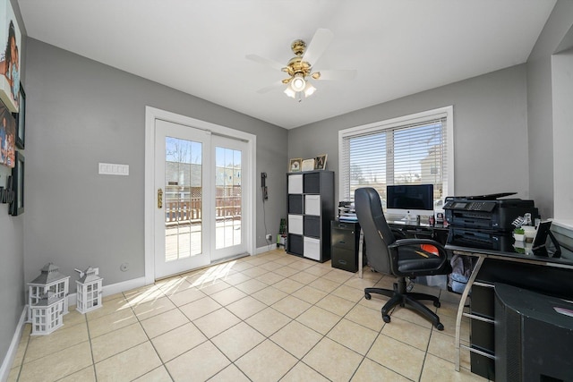 office space featuring baseboards, a ceiling fan, light tile patterned floors, and a healthy amount of sunlight