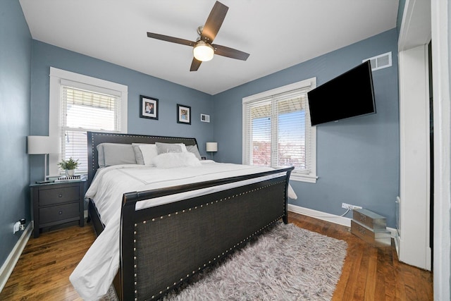 bedroom with baseboards, multiple windows, wood finished floors, and visible vents