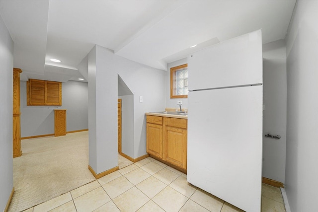 kitchen with a sink, light countertops, freestanding refrigerator, recessed lighting, and baseboards