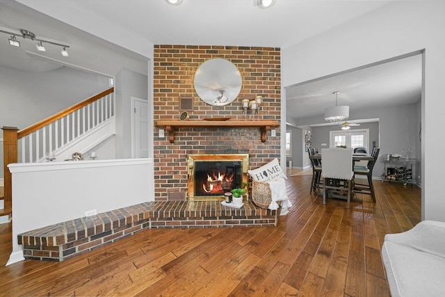 living room featuring visible vents, stairs, a brick fireplace, hardwood / wood-style flooring, and a ceiling fan